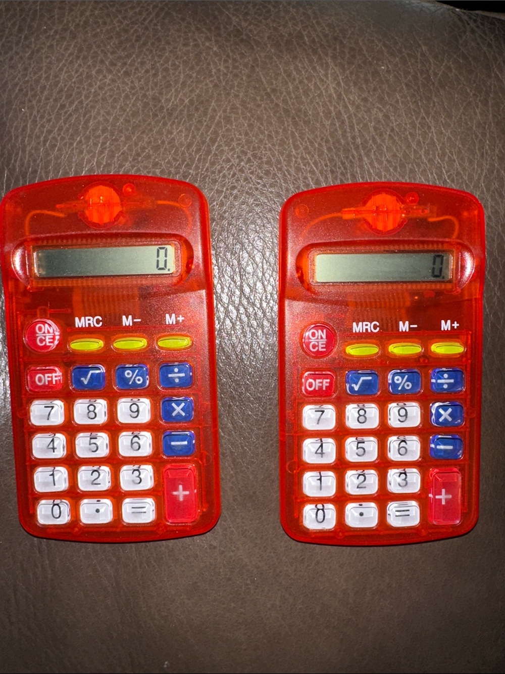 Two translucent red pocket calculators